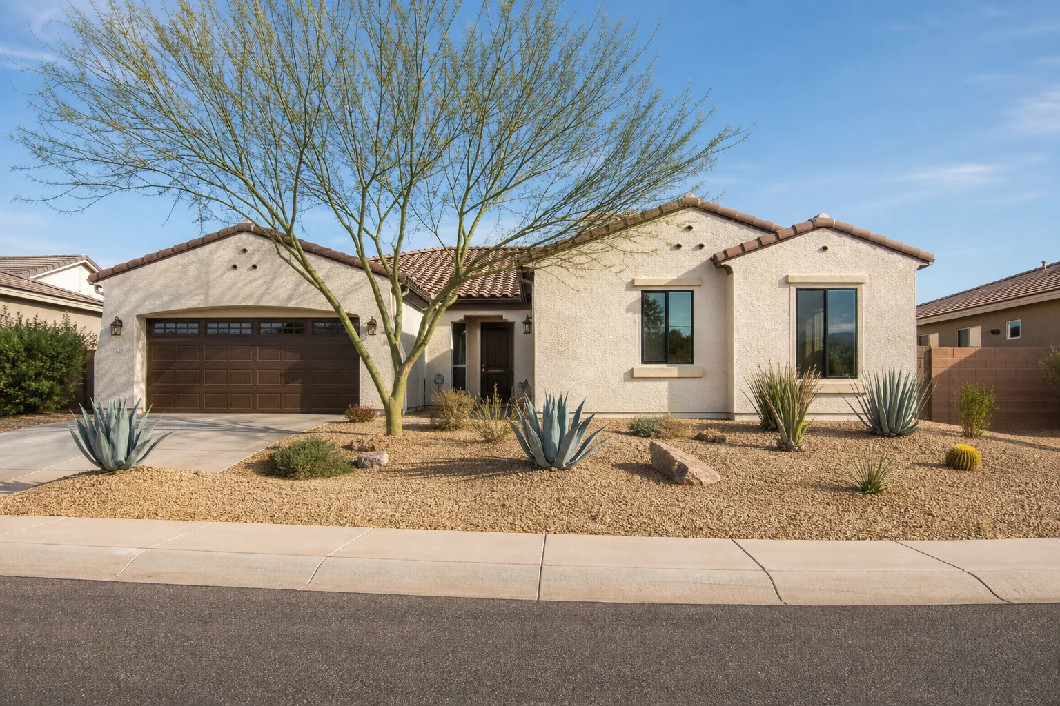 A completed window installation on a modern Arizona stucco home with desert landscaping and a tile roof visible from the street