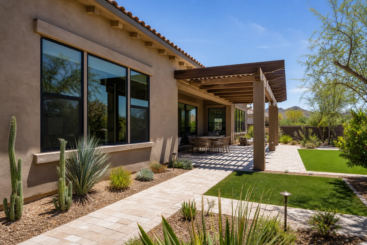 A finished Phoenix-area home exterior showing desert landscaping, a shaded patio, and newly installed windows with clean sightlines