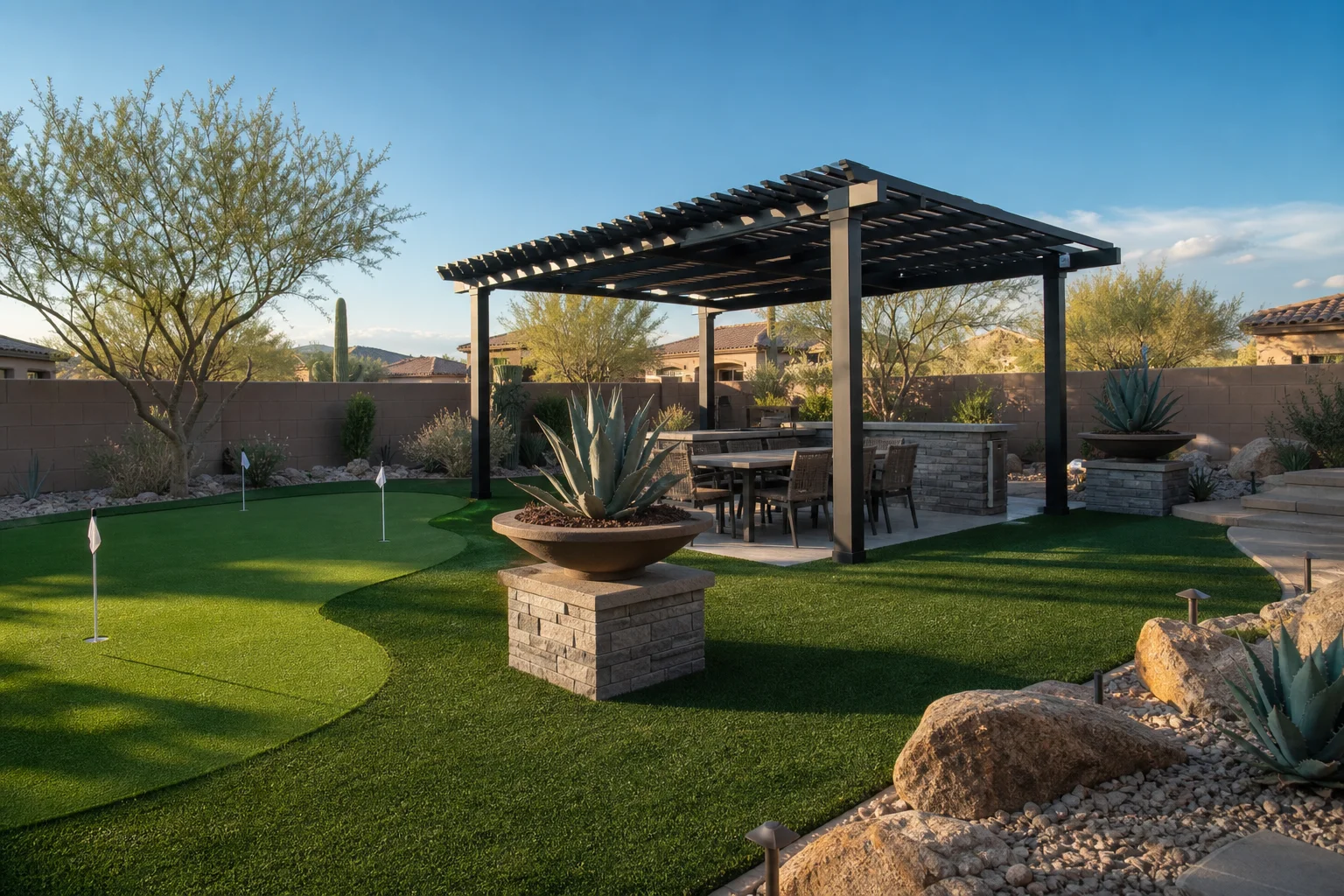 Wide view of a completed artificial turf installation in a Phoenix Arizona residential backyard with desert landscaping borders, pergola shade structure, and a putting green area, afternoon desert light, no people