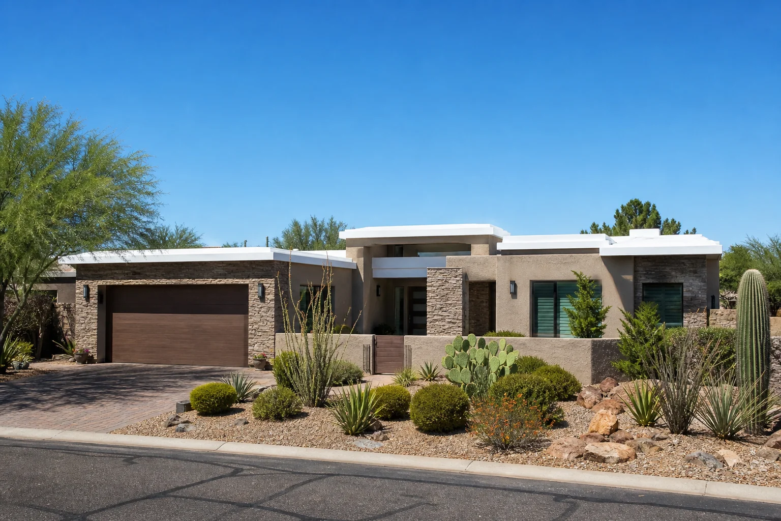 Arizona residential home exterior with a white coated flat roof under clear desert sky and desert landscaping in the foreground